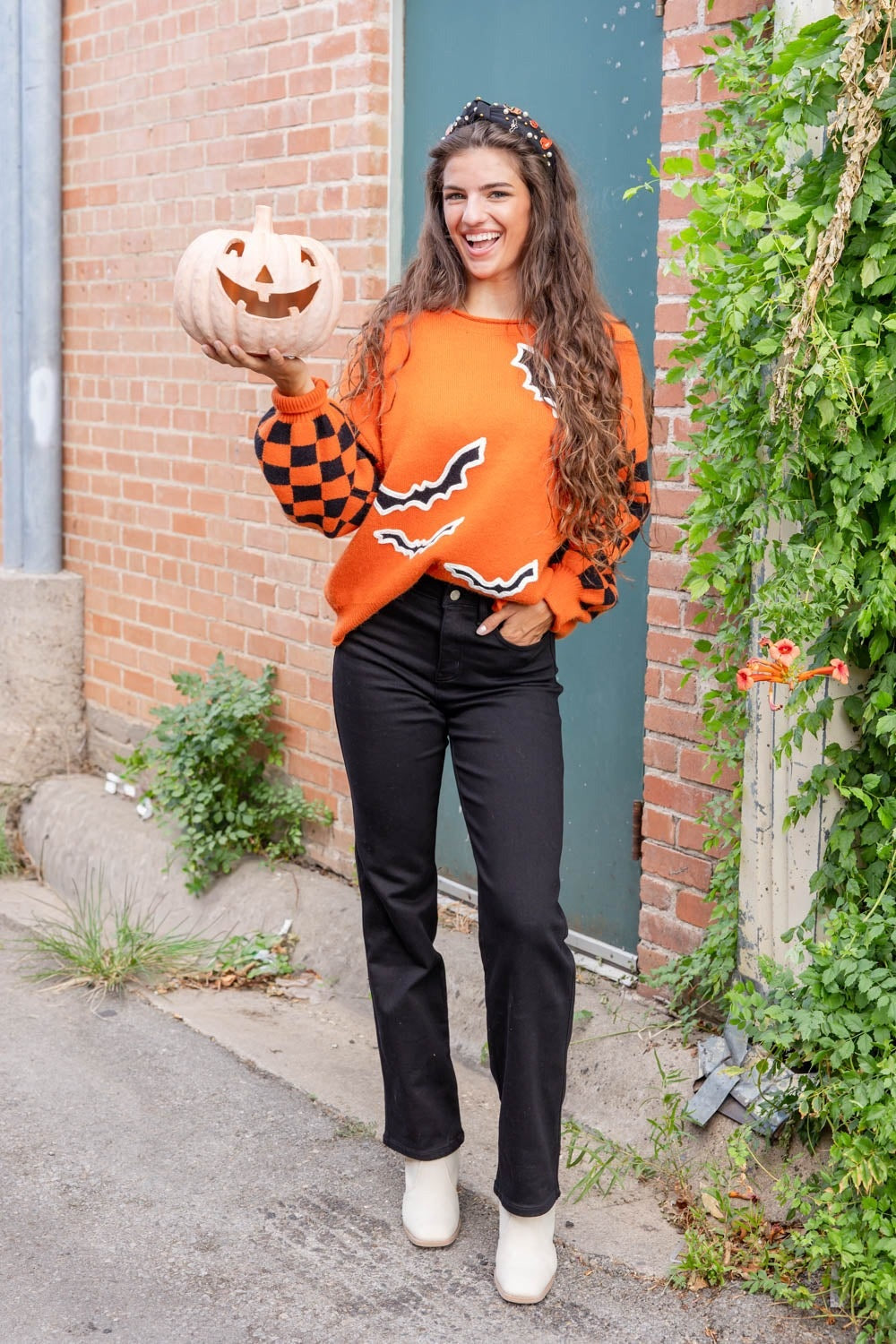 Oranje vleermuistrui met zwarte jeans en een pompoen
