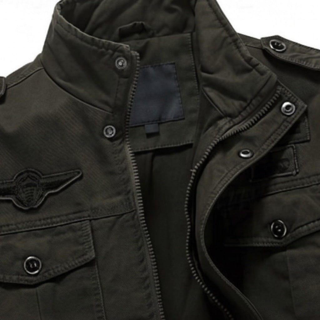 Donkergroene militaire jas met opstaande kraag, borstzak en vliegtuigembleem, close-up | Boutique Moda
