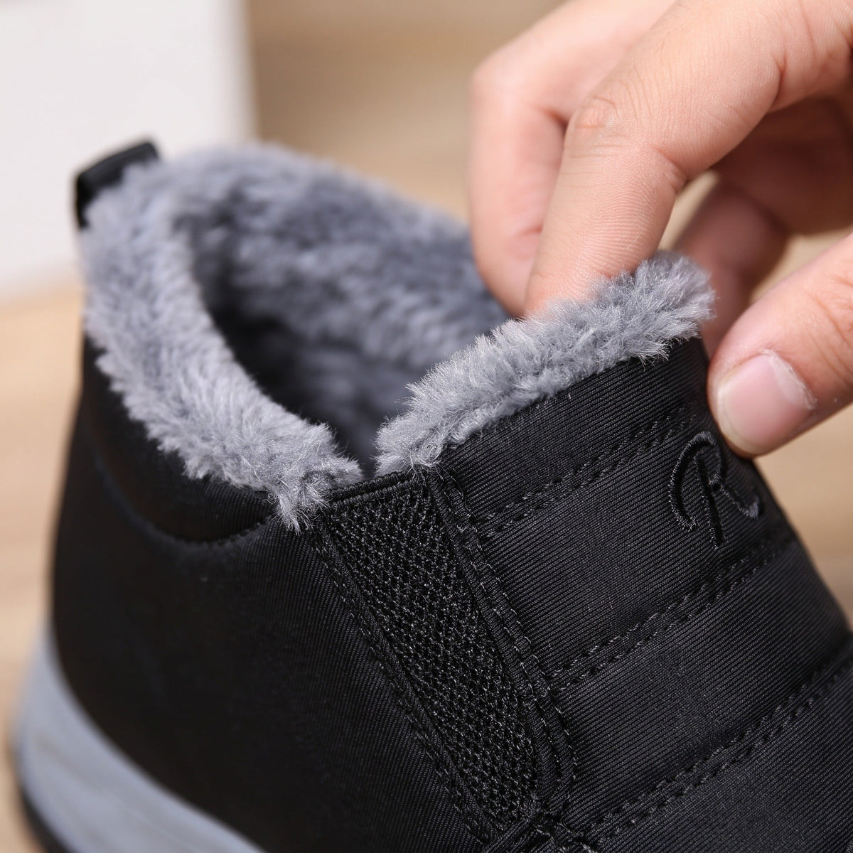 Hand toont grijze warme voering in zwarte instap sneaker close-up | Boutique Moda