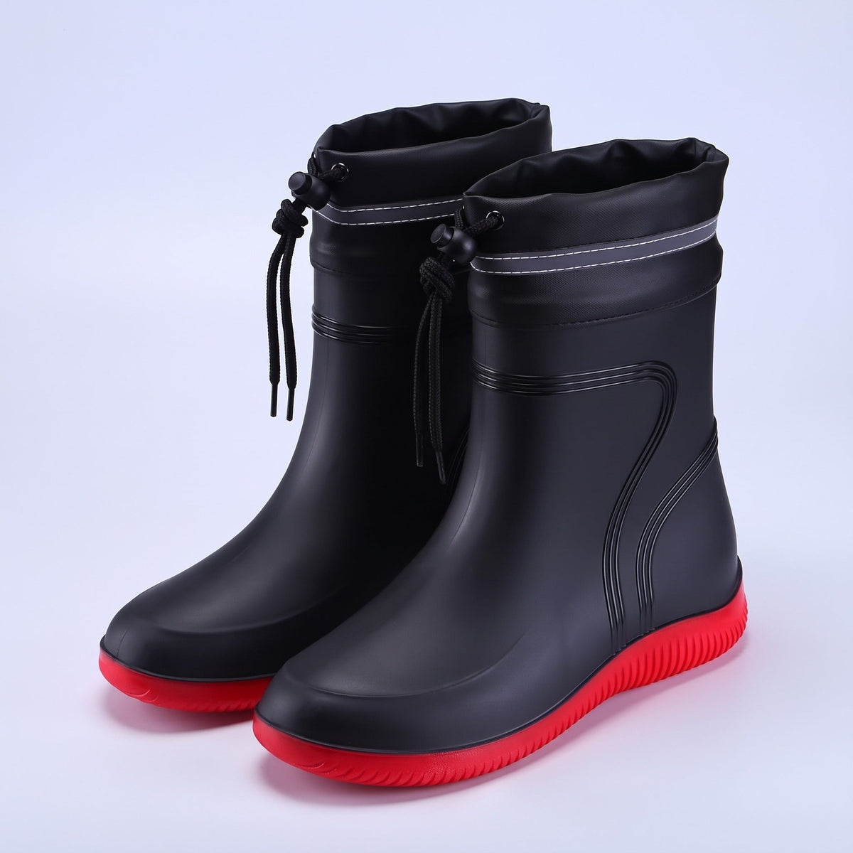 Zwarte regenlaarzen met rode zool, los op witte achtergrond | Boutique Moda