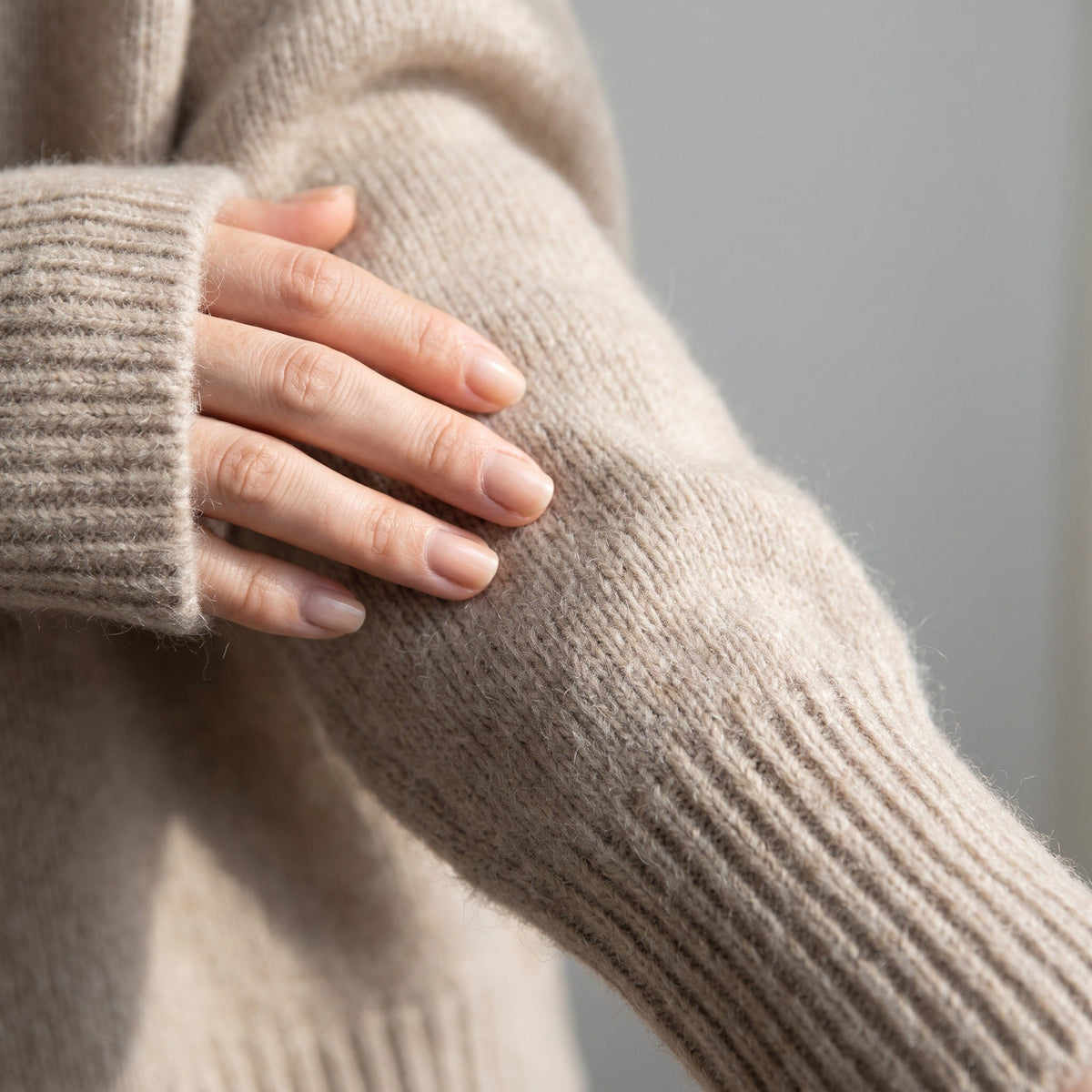 Beige gebreide oversized coltrui, close-up van mouw, gedragen door persoon | Boutique Moda