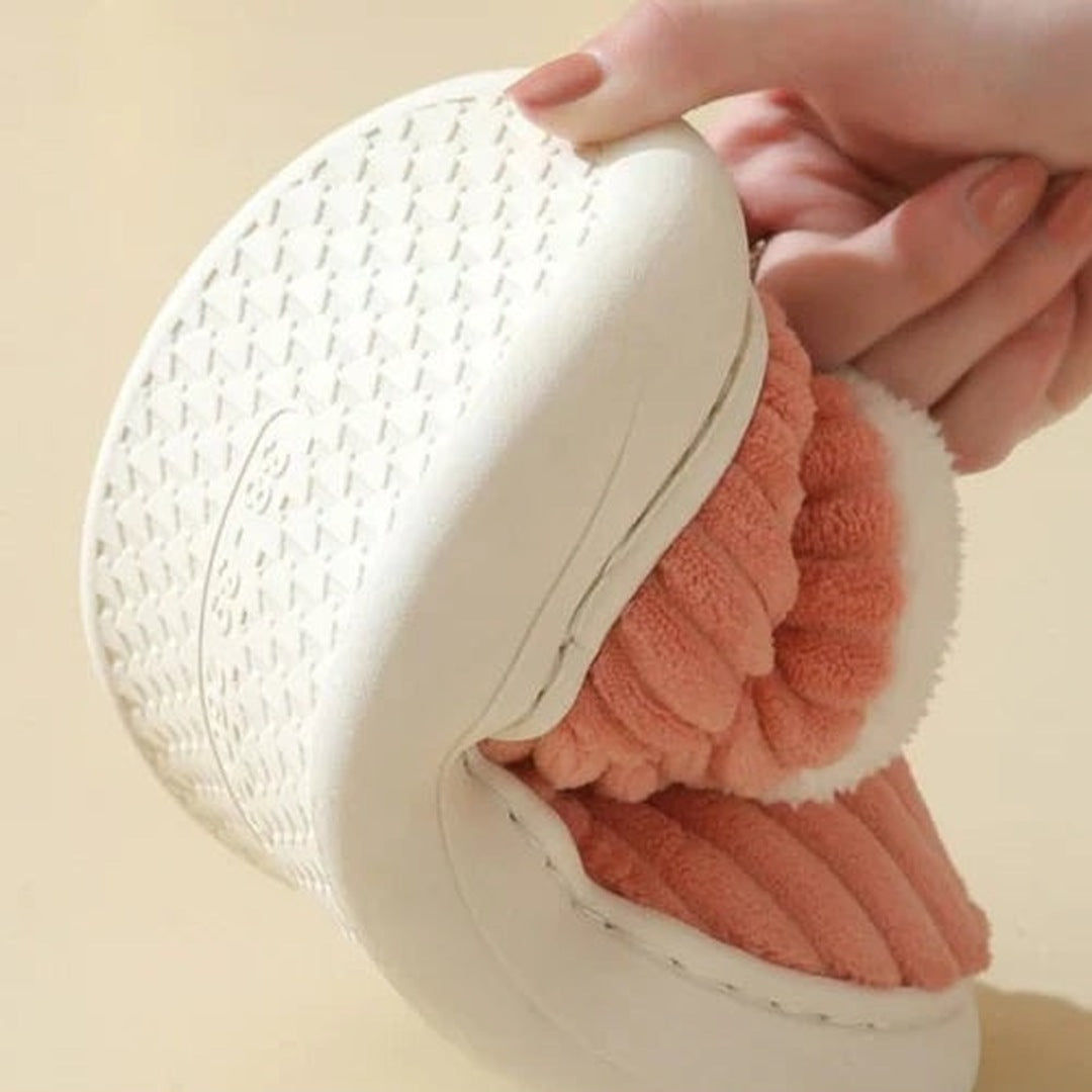 Witte pantoffel met perzikkleurige pluche voering, vastgehouden door een hand | Boutique Moda
