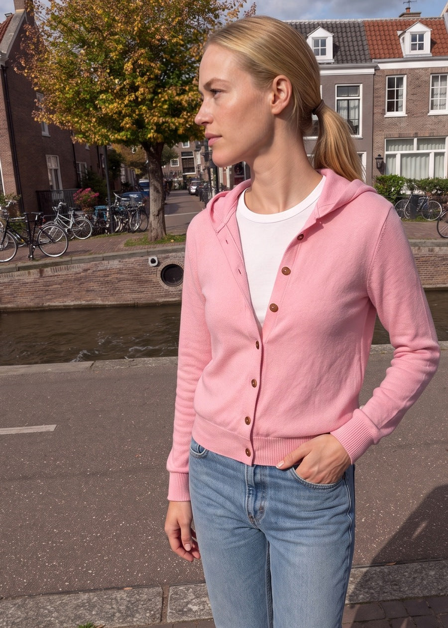 Vrouw in een roze capuchonvest met knoopsluiting aan een Amsterdamse gracht