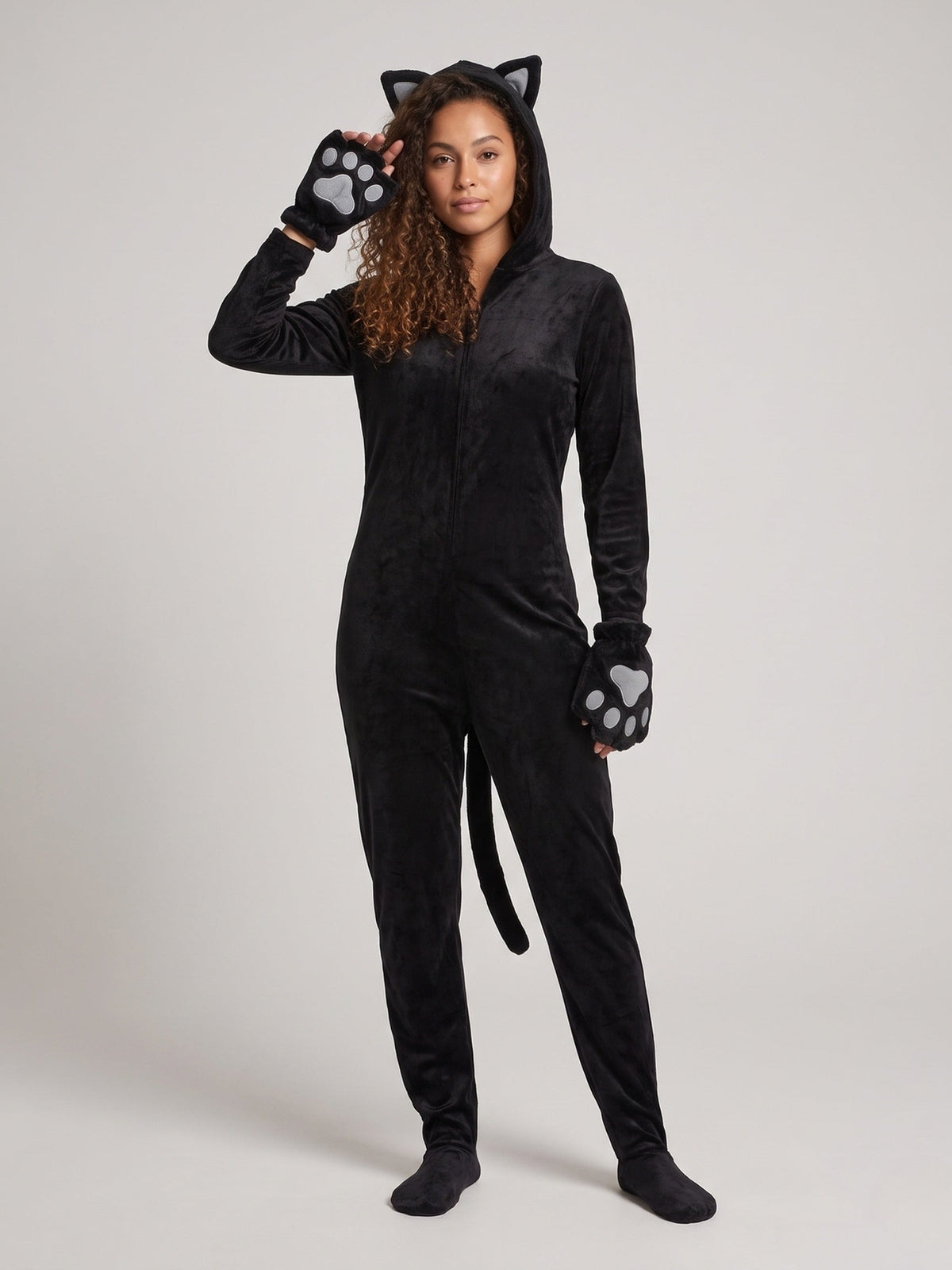 Vrouw in een zwarte pluche katten onesie met capuchon, oortjes en pootjeshandschoenen