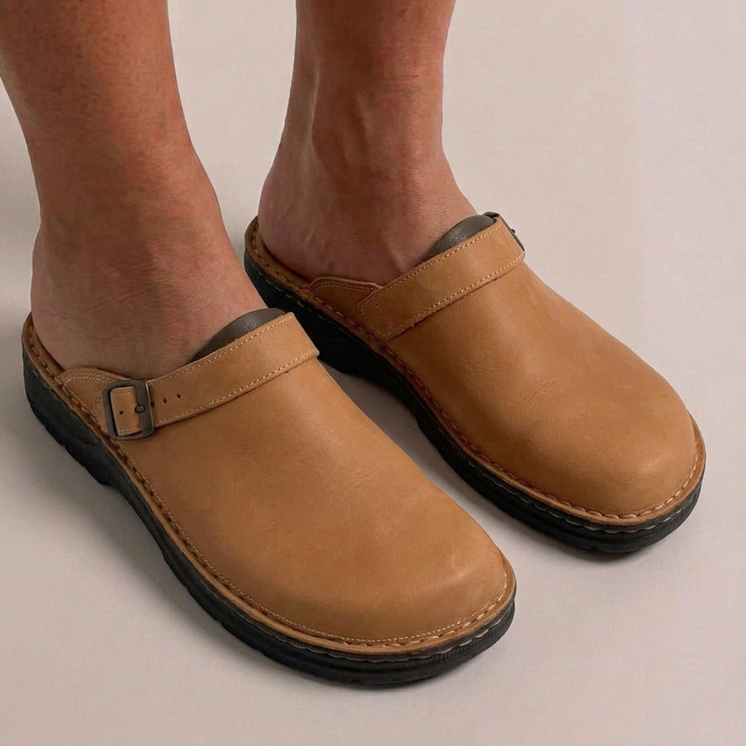 Camelkleurige vegan leren clogs met gesp, gedragen aan voeten op beige achtergrond | Boutique Moda