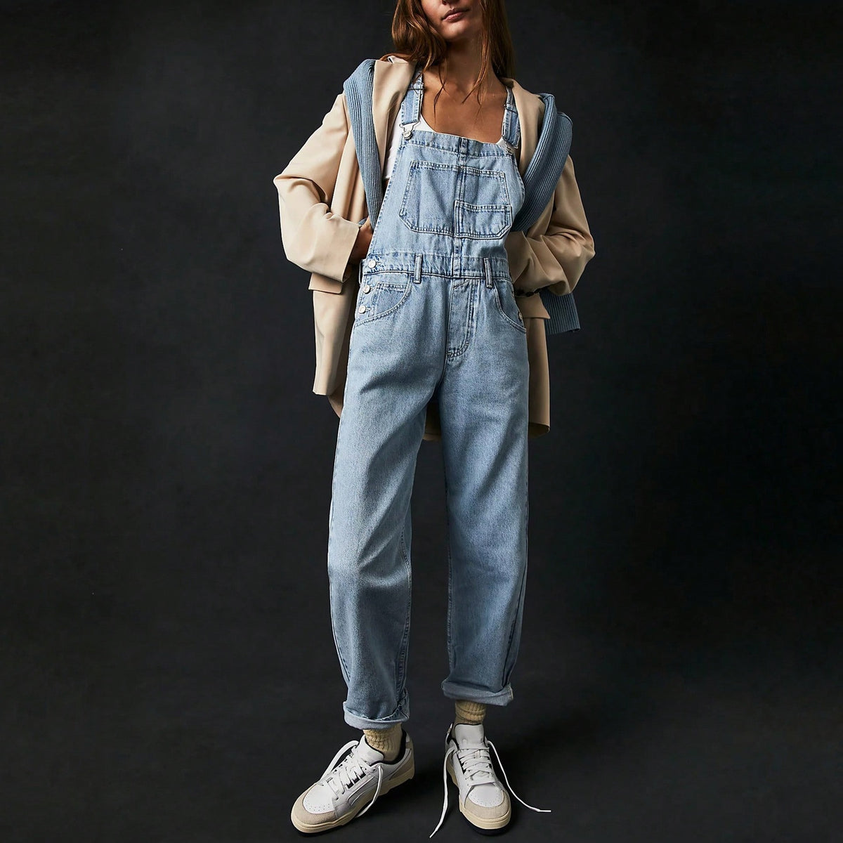 Lichtblauwe denim tuinbroek gedragen door vrouw met beige jas en sneakers | Boutique Moda