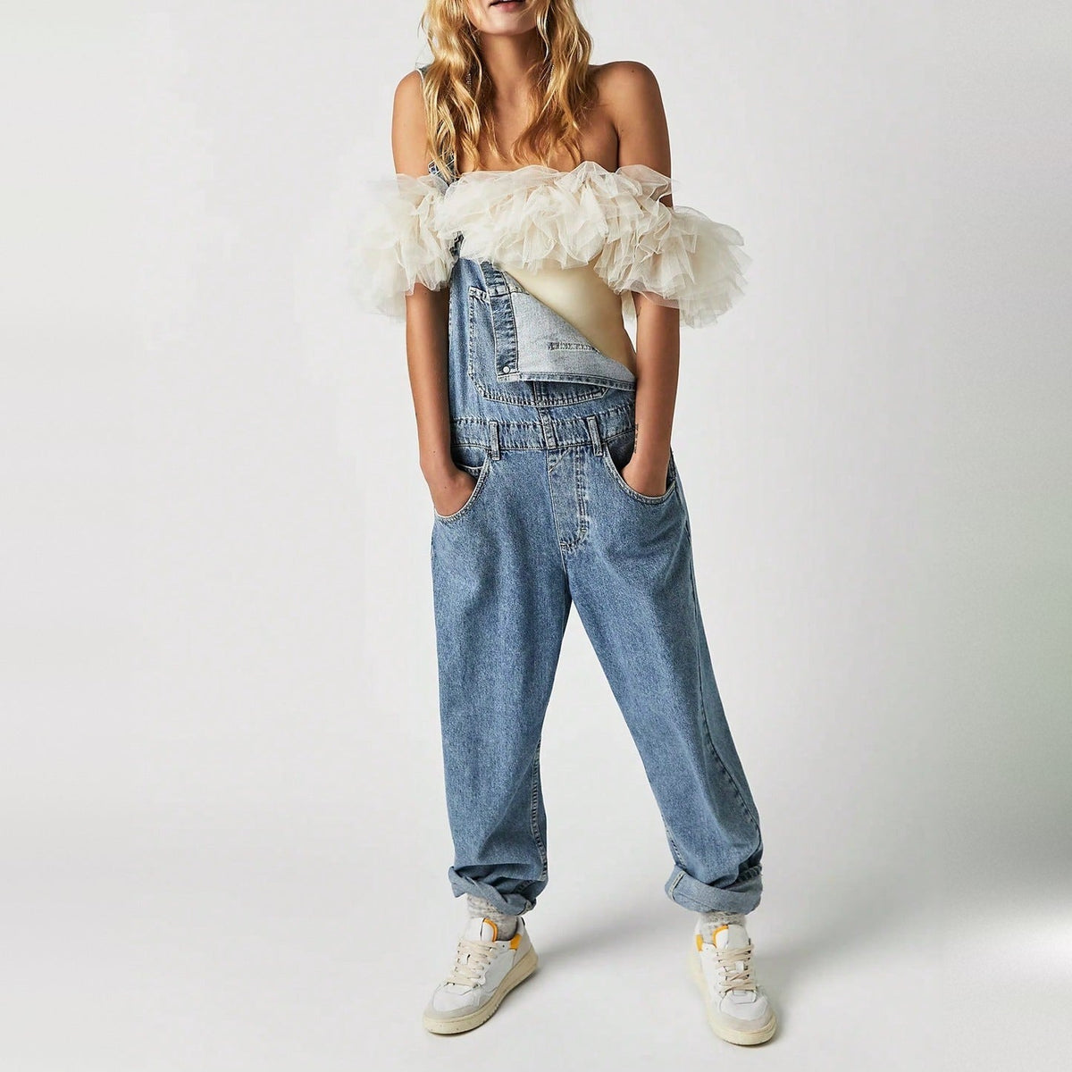 Blauwe denim tuinbroek los model, gedragen door vrouw met witte sneakers | Boutique Moda