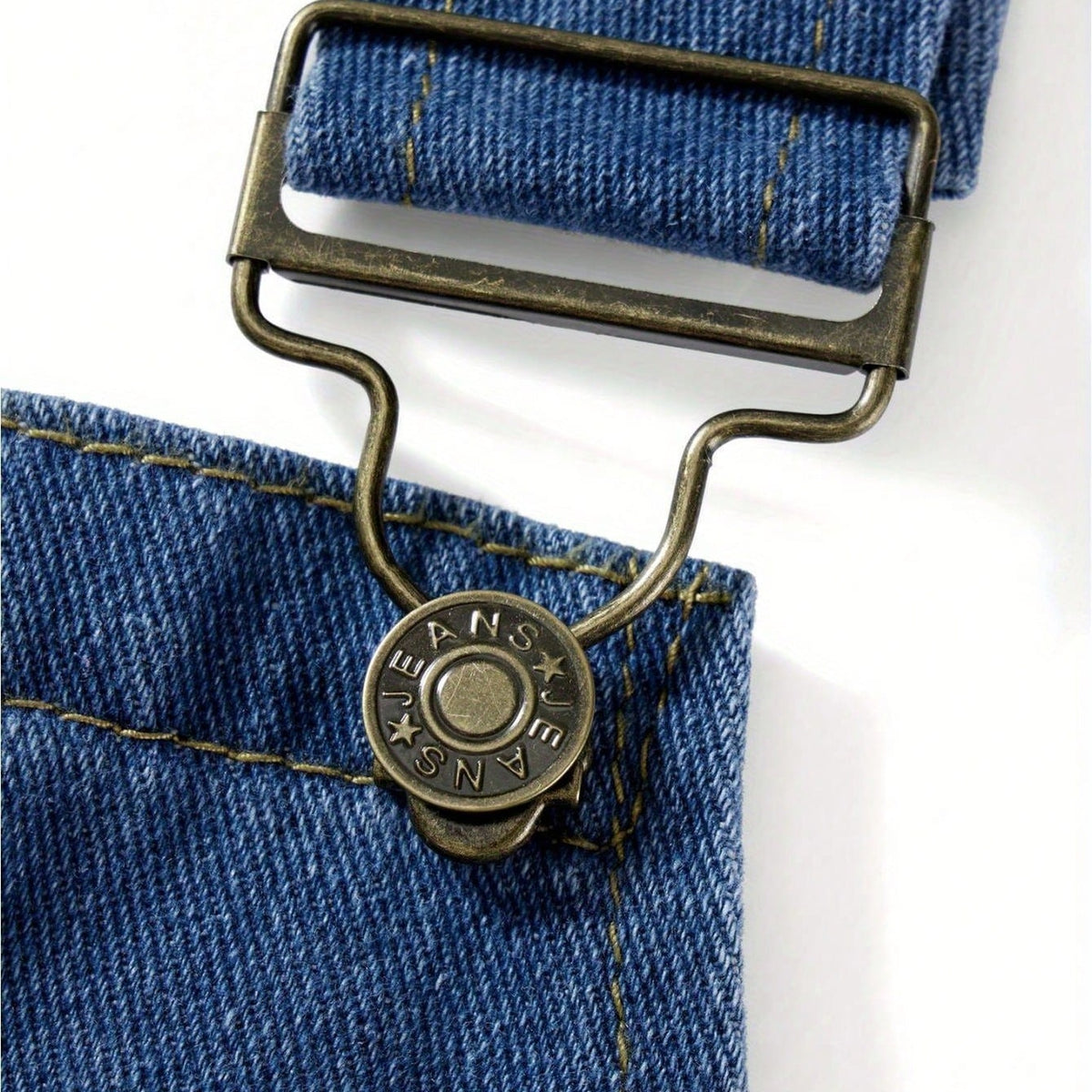 Close-up van blauwe denim tuinbroek met metalen gesp en knoop | Boutique Moda