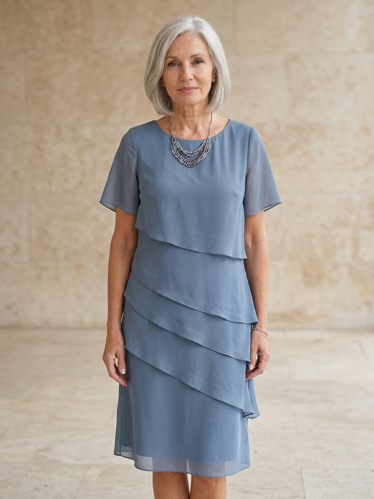 Blauwgrijze chiffon jurk met korte mouwen, gedragen door oudere vrouw | Boutique Moda