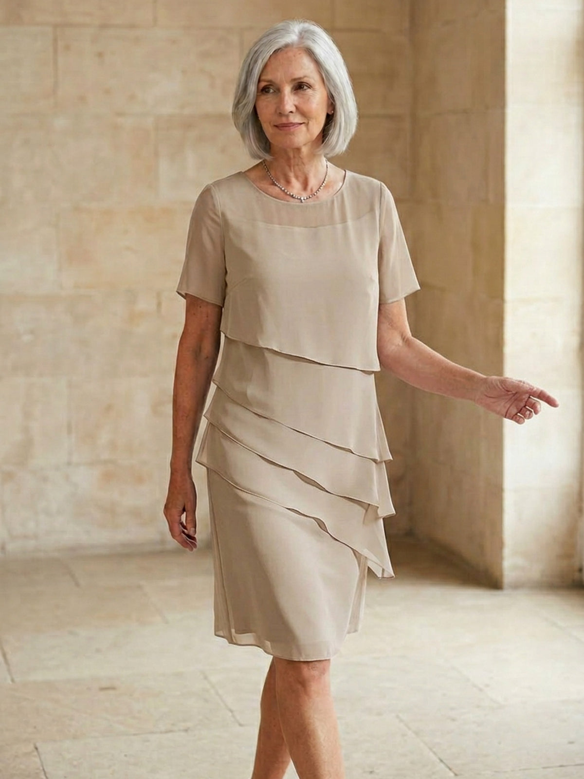 Beige gelaagde chiffon jurk met korte mouwen, gedragen door oudere vrouw | Boutique Moda