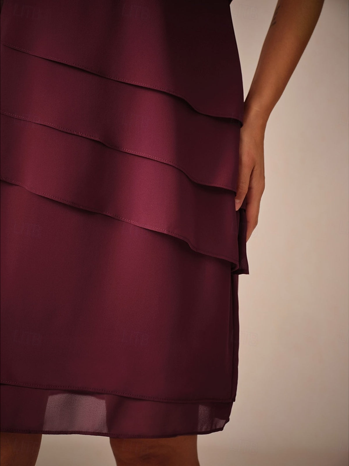 Bordeauxrode gelaagde chiffon jurk met knielengte, gedragen door vrouw, close-up | Boutique Moda