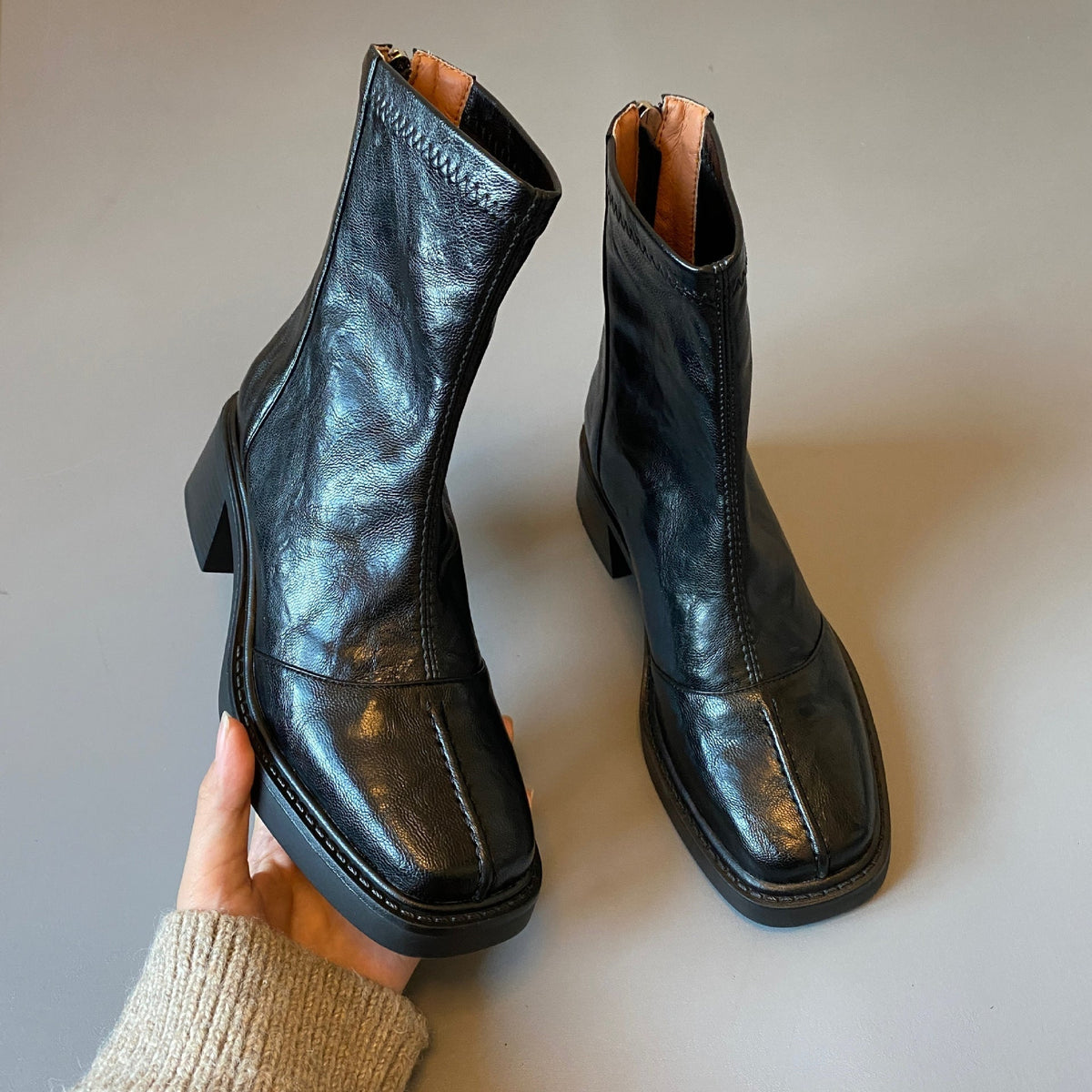 Zwarte enkellaarsjes met blokhak, een hand houdt beide schoenen vast | Boutique Moda