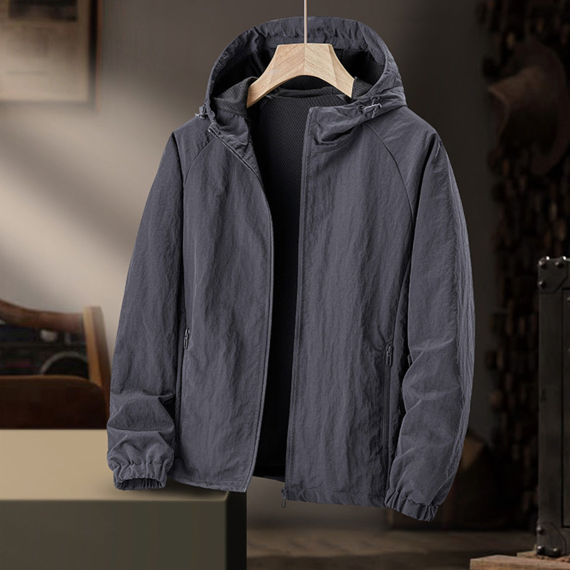 Grijze windjas met capuchon aan hanger, binnenruimte op achtergrond zichtbaar | Boutique Moda