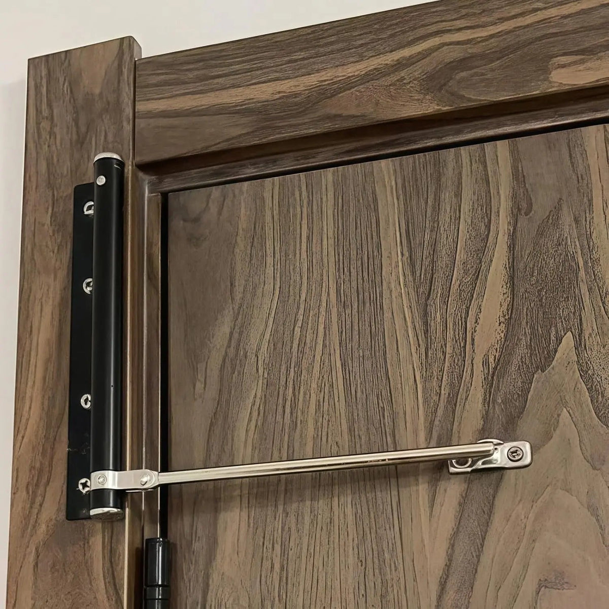 Zilveren deurdranger met veersysteem gemonteerd op houten deur close-up | Boutique Moda