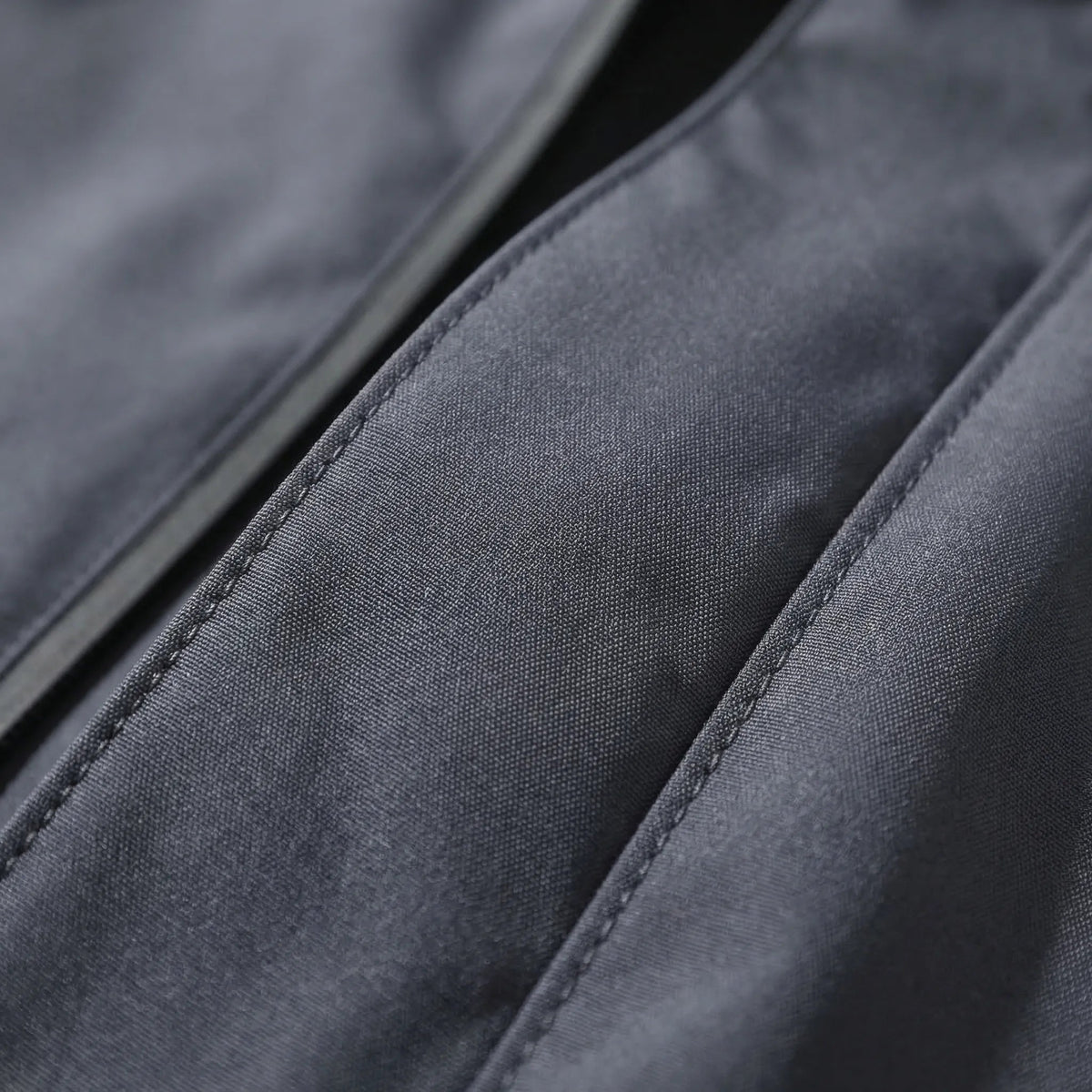 Close-up van donkergrijze regenjas met zichtbare stiksels en naden | Boutique Moda
