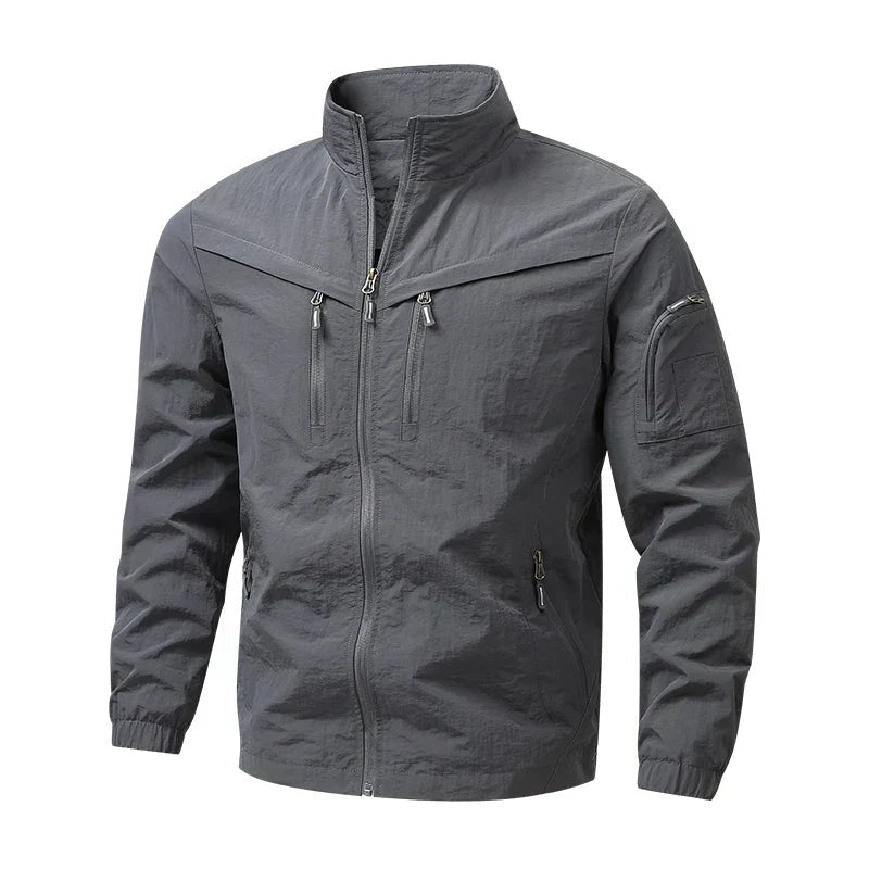 Grijze utility jas met opstaande kraag en meerdere ritszakken, op paspop | Boutique Moda