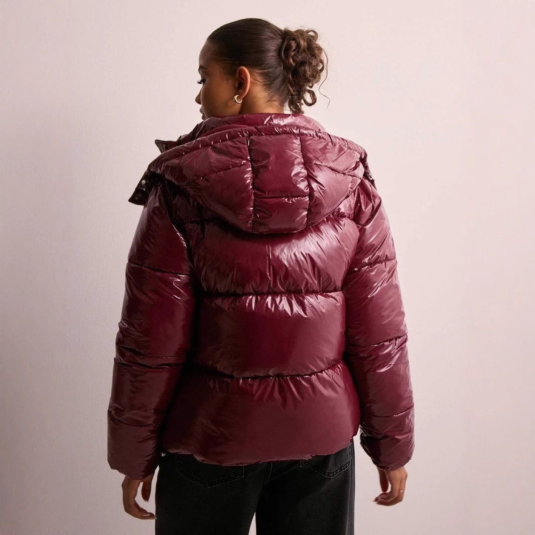 Glanzende bordeauxrode gewatteerde jas met capuchon, gedragen door vrouw op rug | Boutique Moda