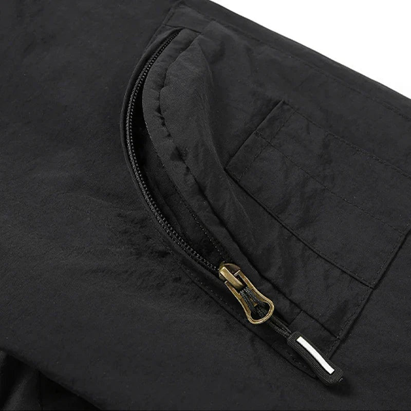 Zwarte jas close-up met ritszak en gouden ritstrekker, plat gefotografeerd | Boutique Moda