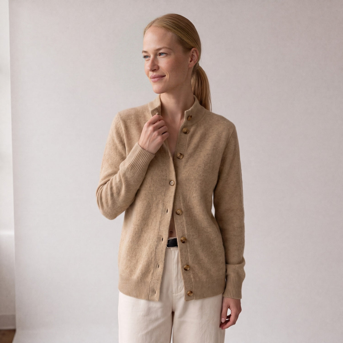 Vrouw in een beige gebreid vest met opstaande kraag