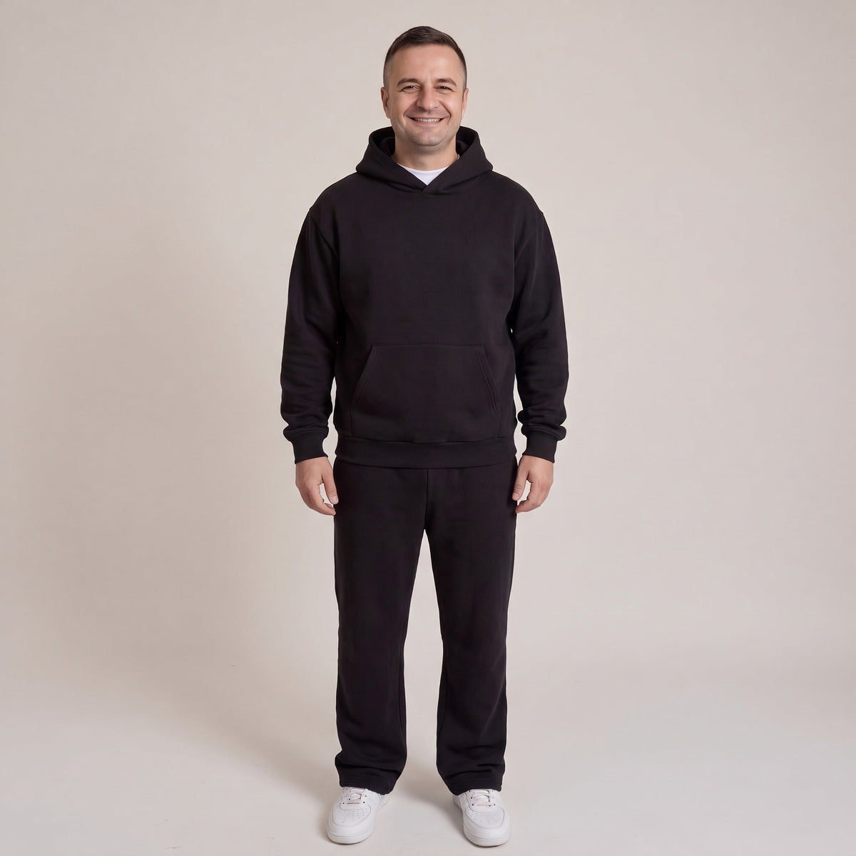 Man draagt zwarte hoodie met joggingbroek, volledige outfit, staand model | Boutique Moda