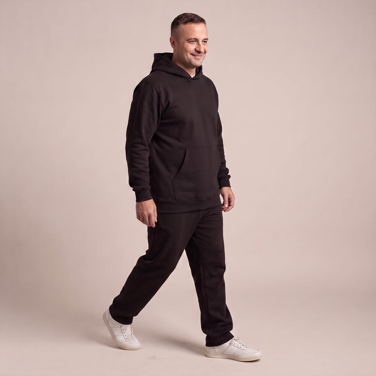 Man draagt zwart joggingpak met hoodie, lopend in fotostudio | Boutique Moda