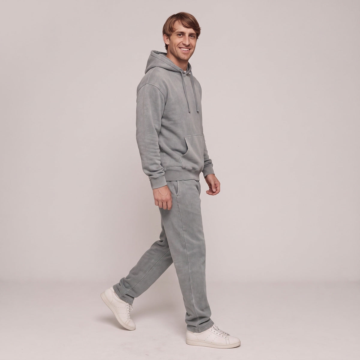 Man draagt grijze hoodie en joggingbroek, lopend, volledige outfit zichtbaar | Boutique Moda