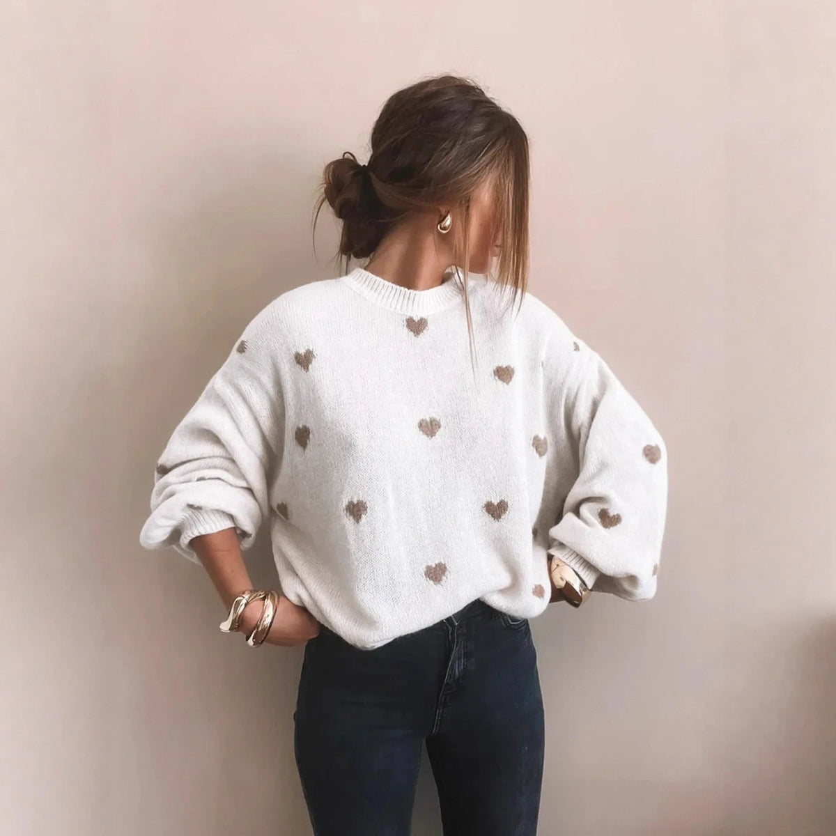 Witte oversized damestrui met ingebreide beige hartjes, gedragen met een donkere jeans