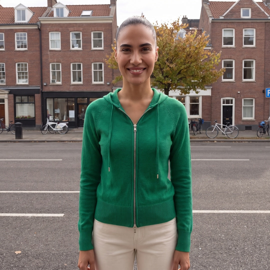 Vrouw draagt het groene gebreide vest met capuchon in een straat in Den Haag | Boutique Moda