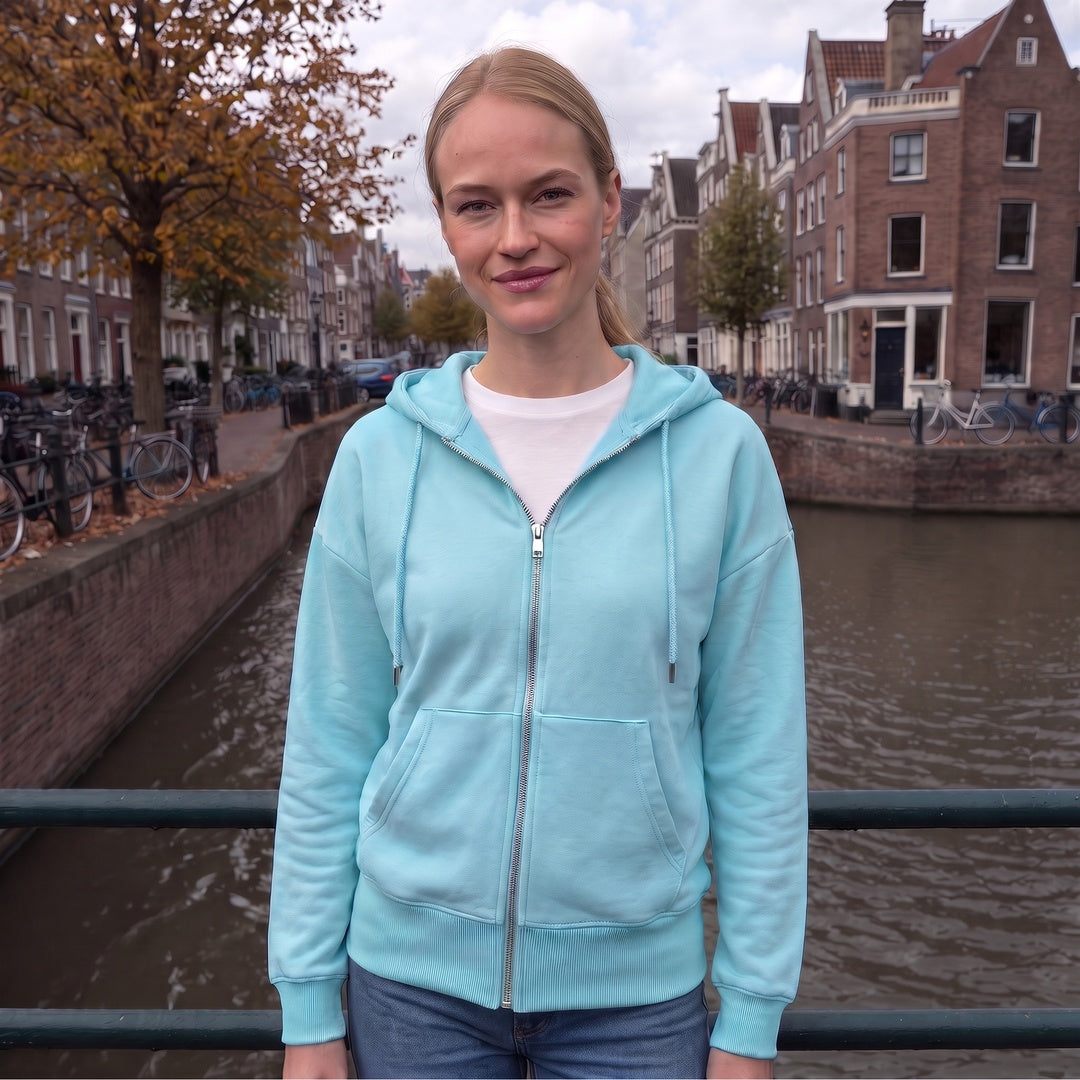 Vrouw draagt het lichtblauwe sweatvest met capuchon op een grachtbrug in Amsterdam | Boutique Moda