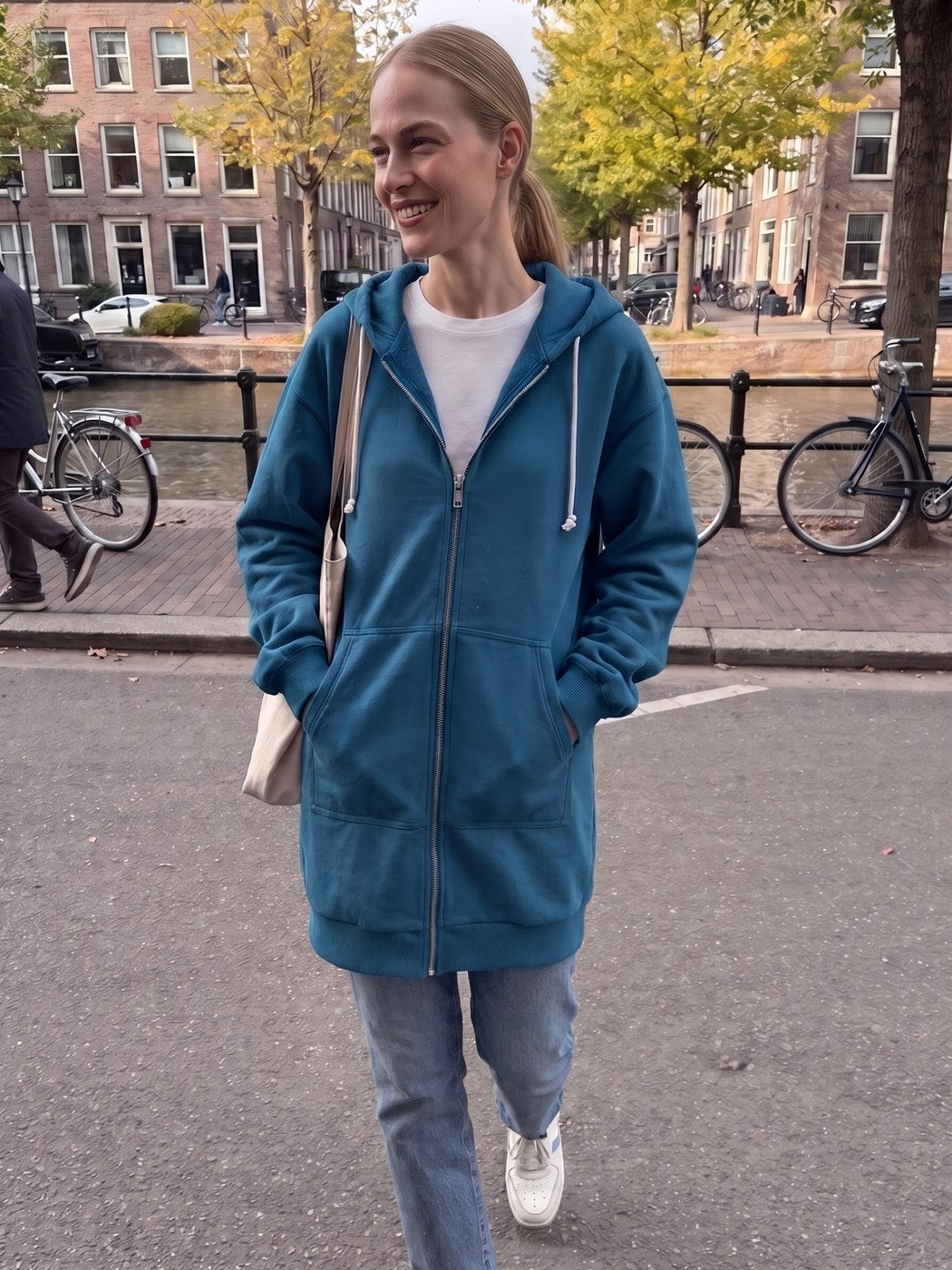 Vrouw draagt het lange blauwe vest langs een gracht in Amsterdam | Boutique Moda