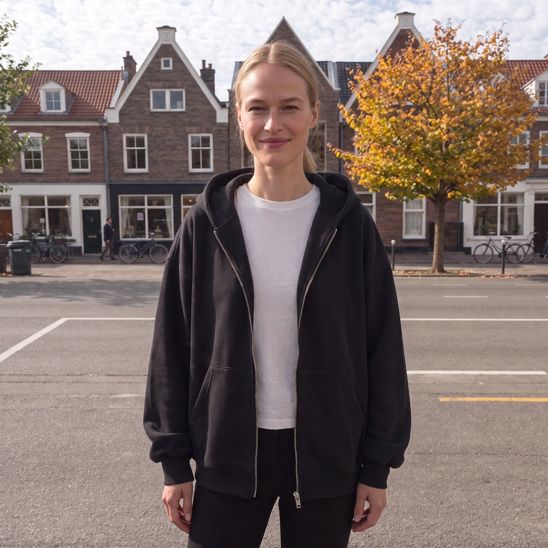 Vrouw draagt het zwarte oversized hoodie vest in een straat in Haarlem | Boutique Moda