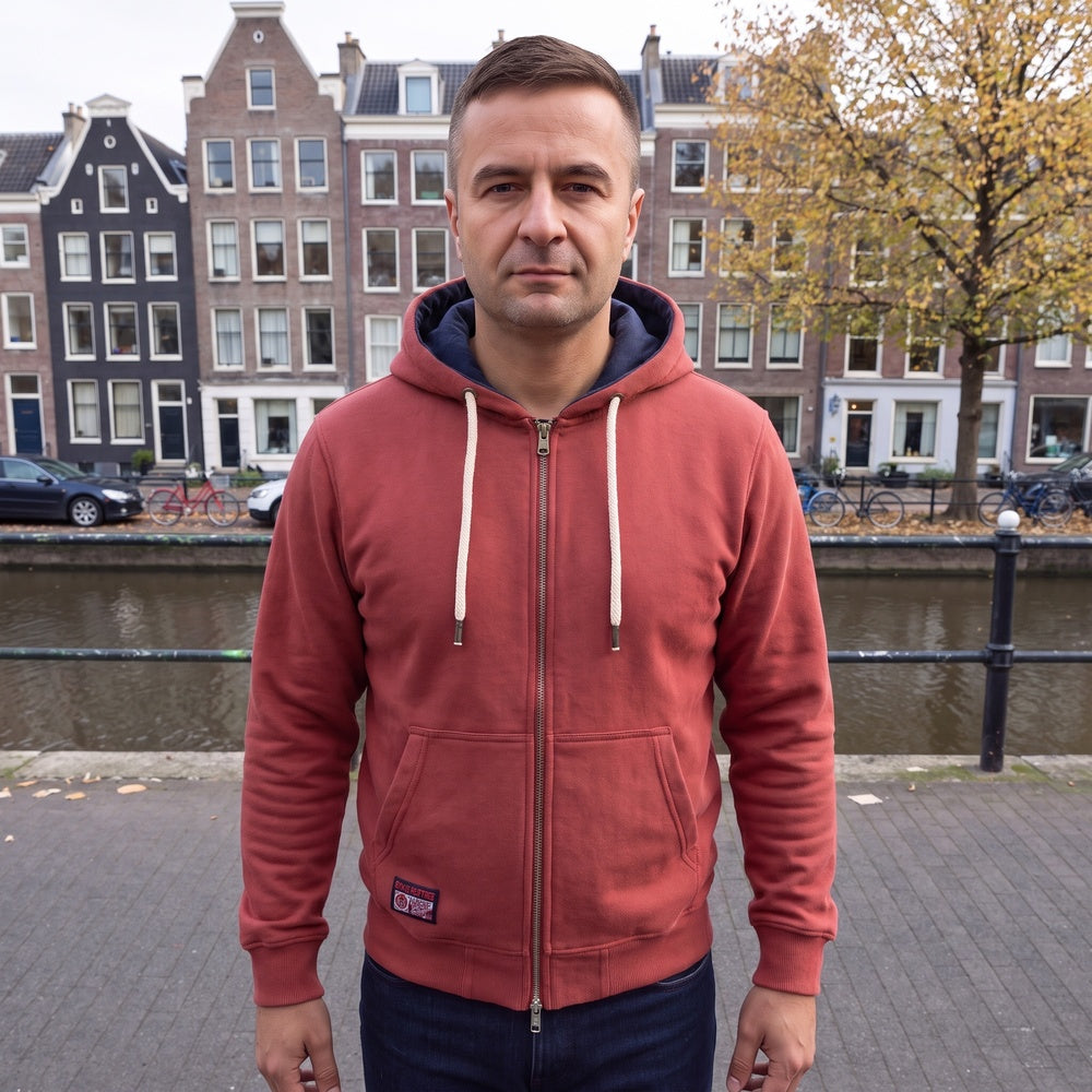 Man draagt de steenrode hoodie met rits aan een gracht in Amsterdam | Boutique Moda