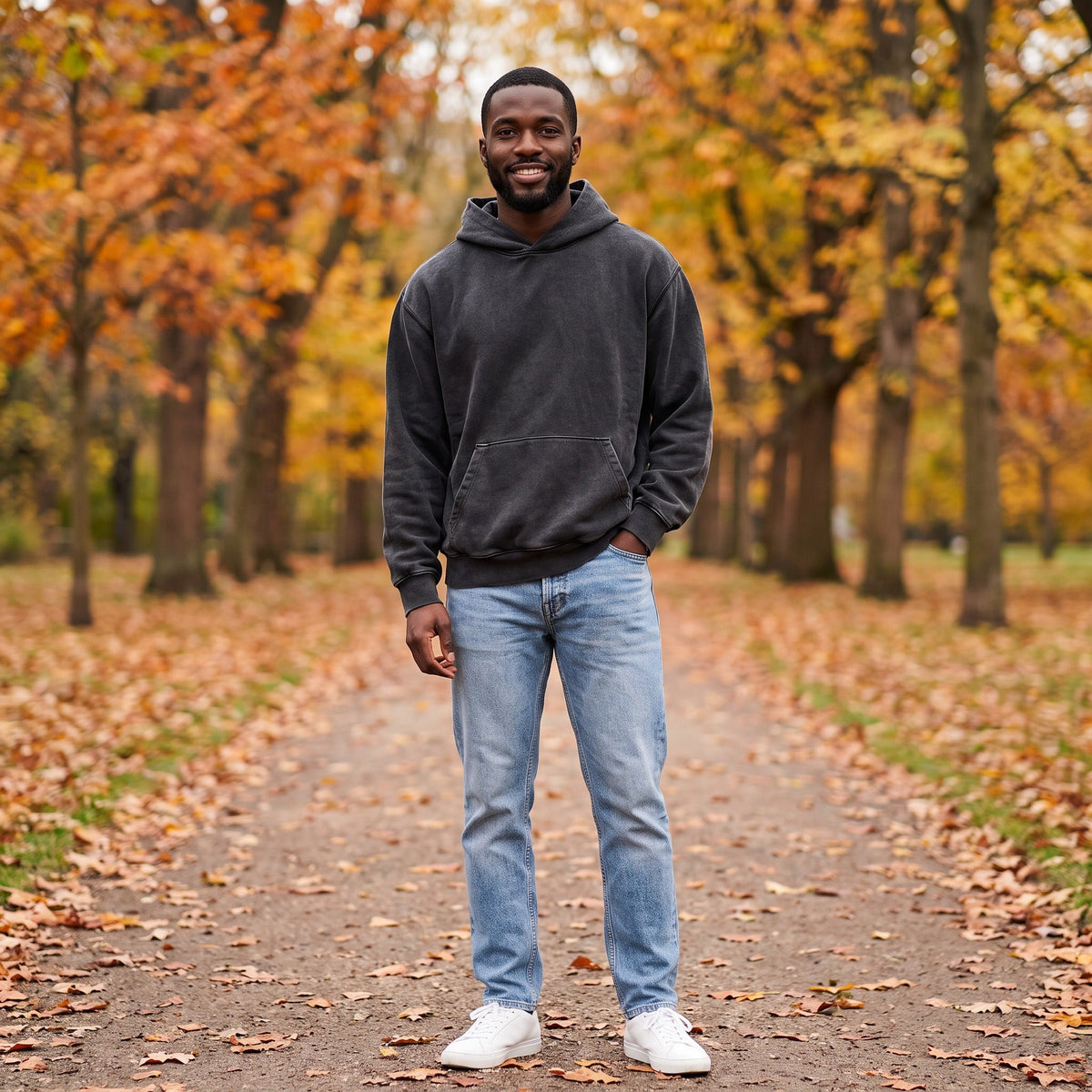 Man draagt grijze oversized hoodie met jeans in herfstpark | Boutique Moda