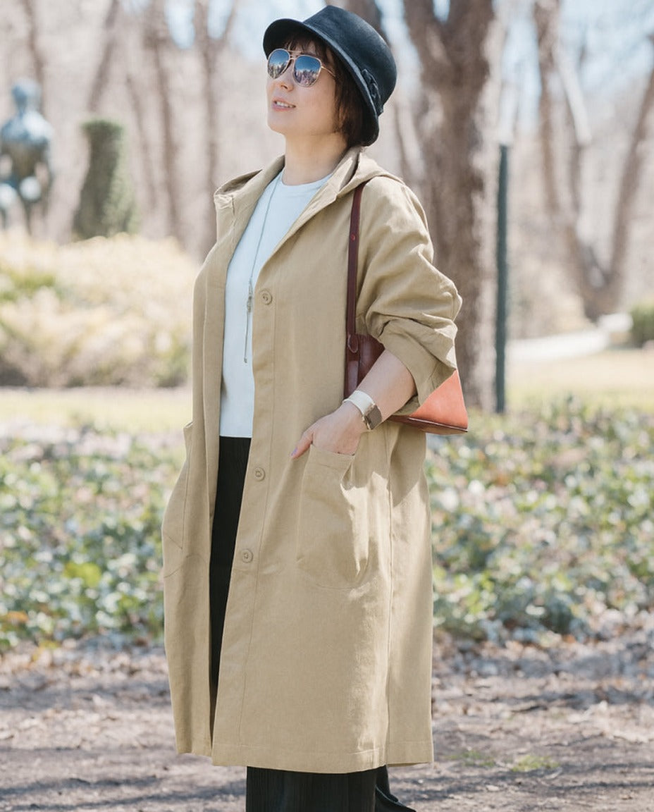 Beige oversized regenjas met capuchon, gedragen door vrouw buiten | Boutique Moda
