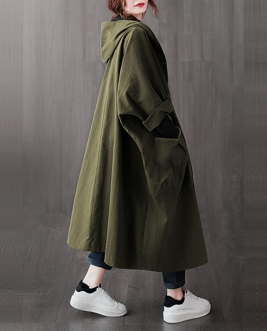 Groene oversized regenjas met capuchon, gedragen door vrouw met sneakers | Boutique Moda