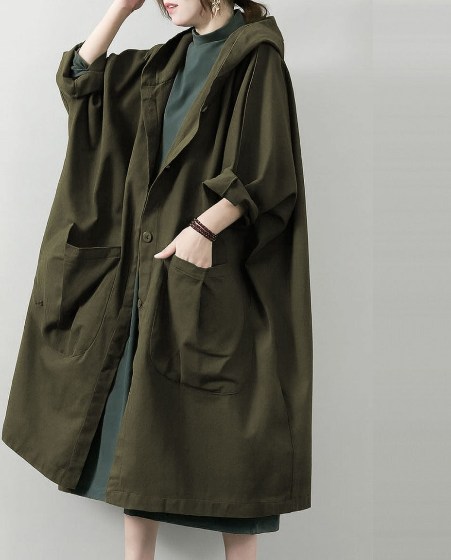 Legergroene oversized regenjas met capuchon, gedragen door vrouw met zakken | Boutique Moda