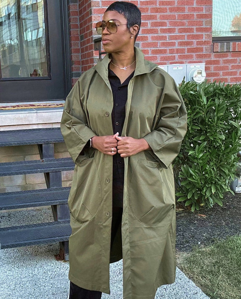Olijfgroene oversized regenjas gedragen door vrouw met zonnebril buiten | Boutique Moda