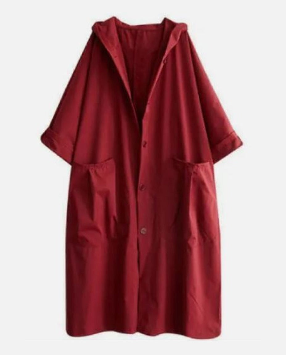 Rode lange jas met capuchon en zakken, uitgestald plat neergelegd | Boutique Moda