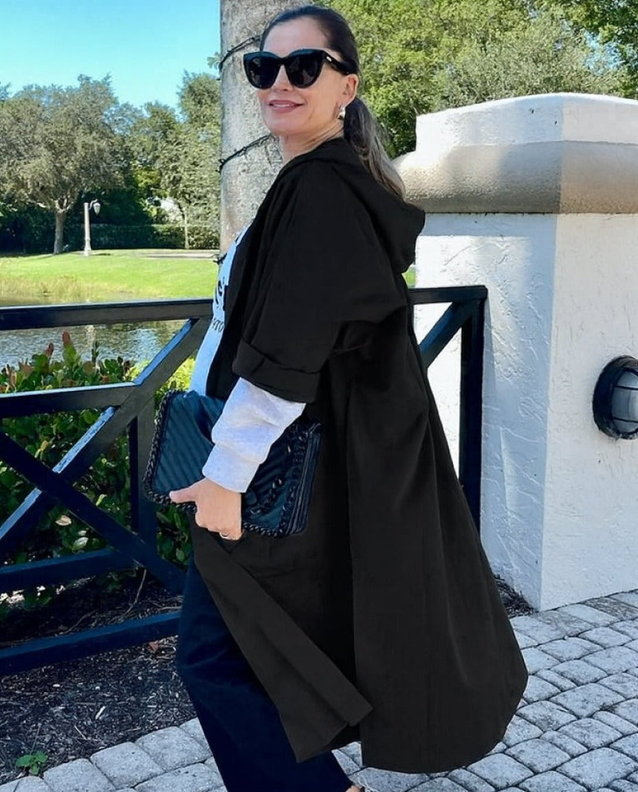 Vrouw draagt lange zwarte oversized regenjas met capuchon buiten | Boutique Moda