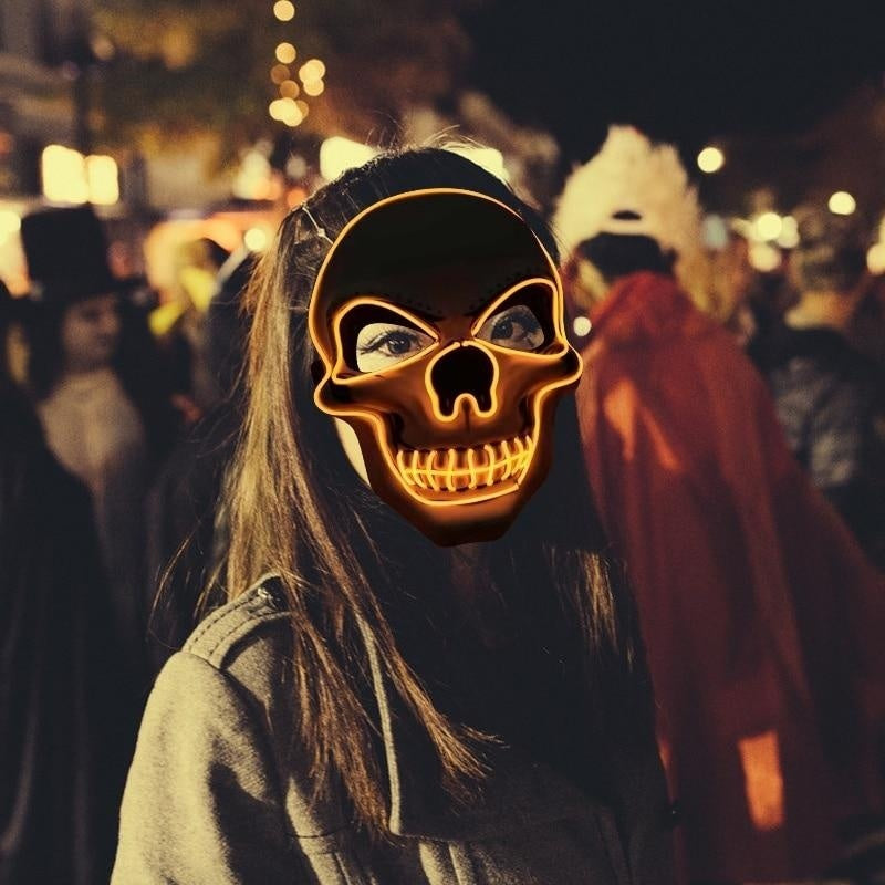 Vrouw met het oranje LED doodskop masker op een avondevenement
