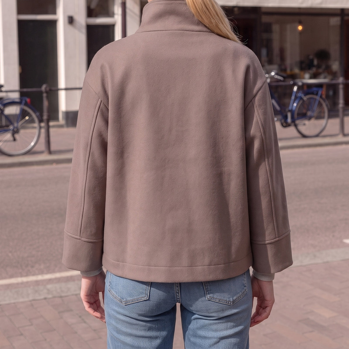Achterkant van de taupe korte jas met opstaande kraag | Boutique Moda