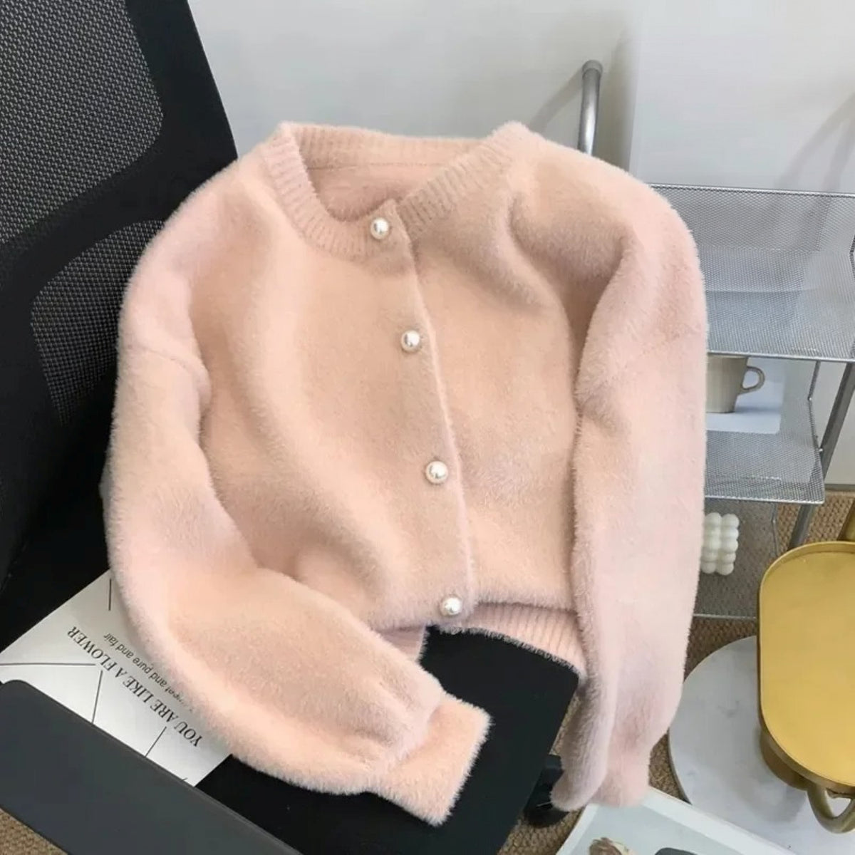 Kort pluizig vestje in roze met parelknopen