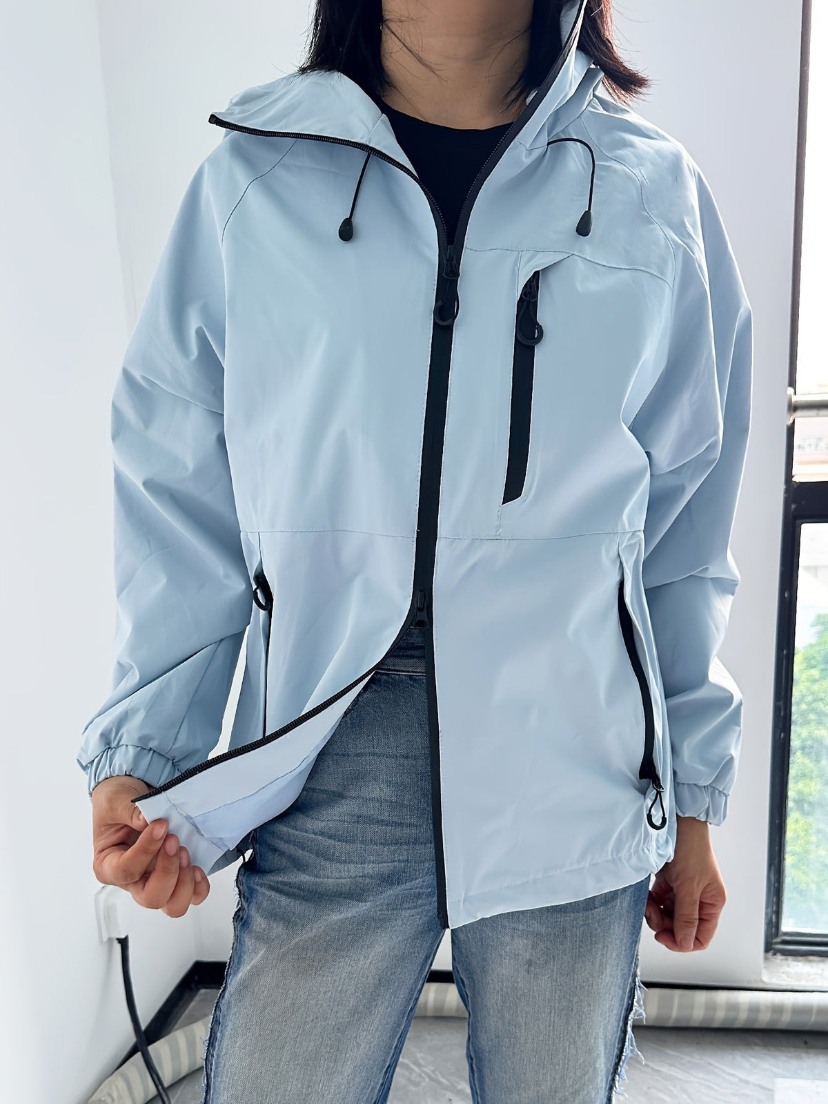 Lichtblauwe regenjas, zoom uitgetrokken om de stof te tonen | Boutique Moda