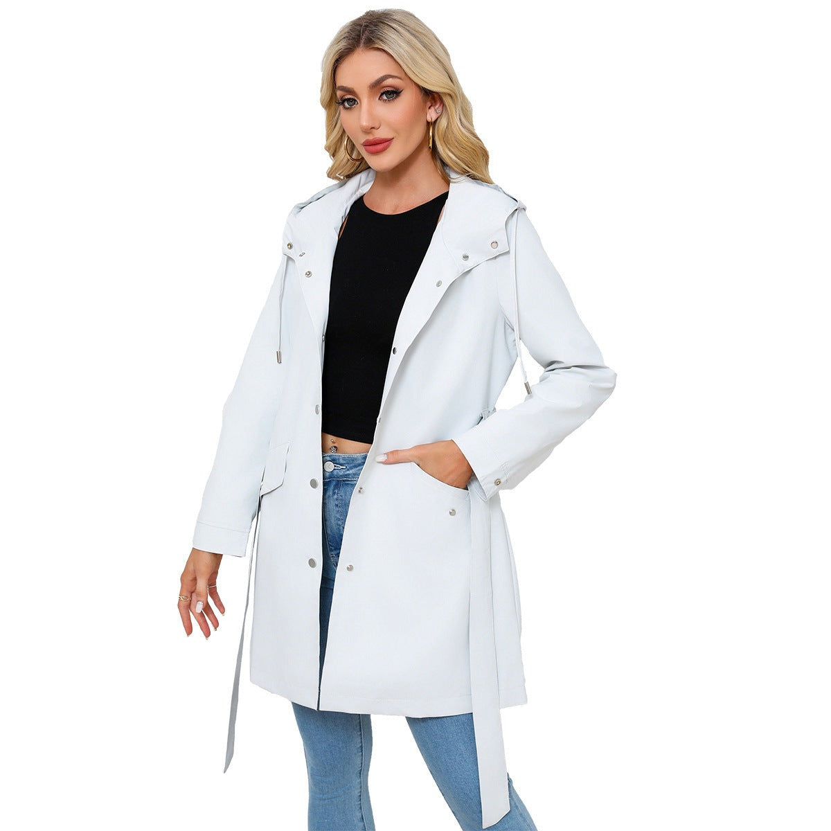 Lichtgrijze trenchcoat met capuchon, open over een zwarte top en jeans | Boutique Moda