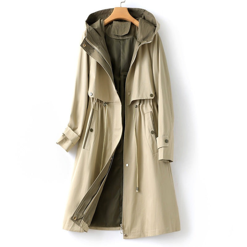 Beige trenchcoat met capuchon, trekkoord in de taille en olijfgroen binnenbeleg, aan een kledinghanger | Boutique Moda