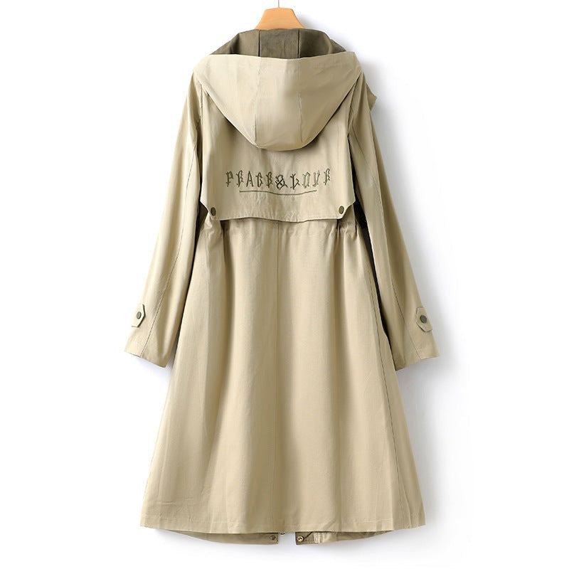 Achterkant van de beige trenchcoat met capuchon, geknoopte pas en geborduurde letters | Boutique Moda