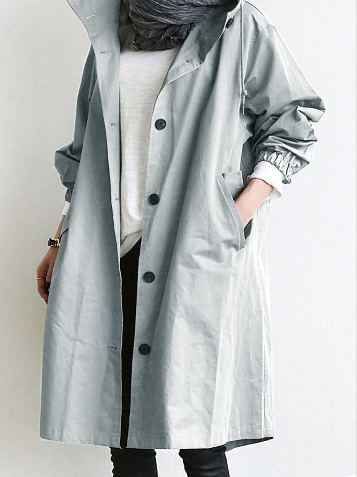 Trenchcoat met capuchon in lichtgrijs, open gedragen over een wit shirt | Boutique Moda