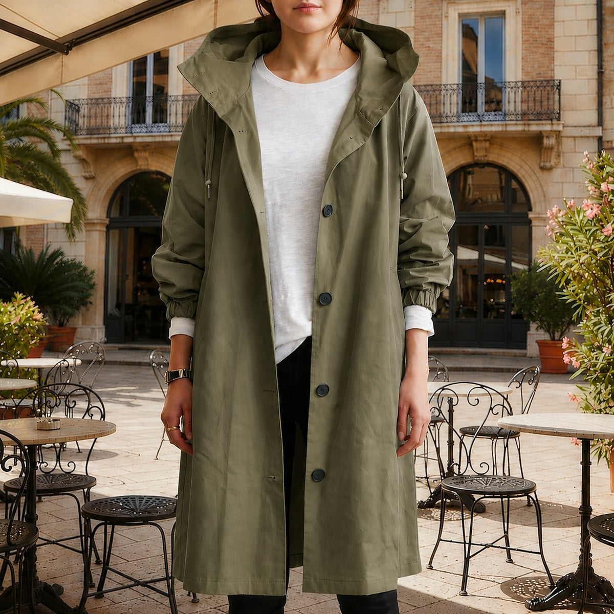 Olijfgroene lange trenchcoat met capuchon en knoopsluiting, open gedragen over een wit T-shirt | Boutique Moda