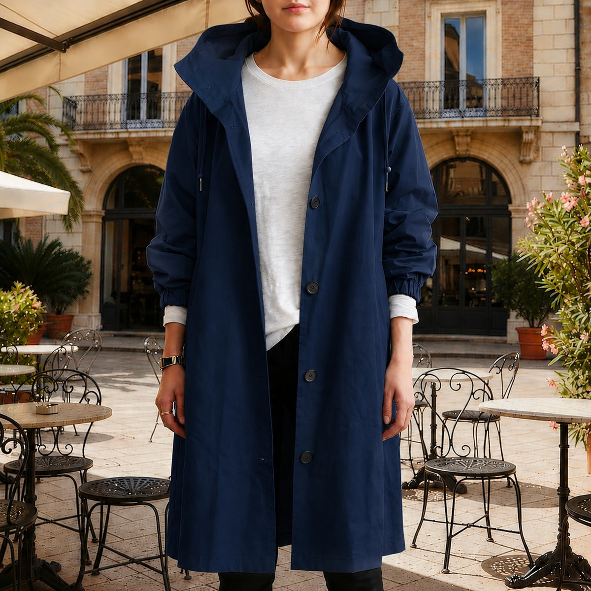 Marineblauwe lange trenchcoat met capuchon en knoopsluiting, open gedragen over een wit T-shirt | Boutique Moda