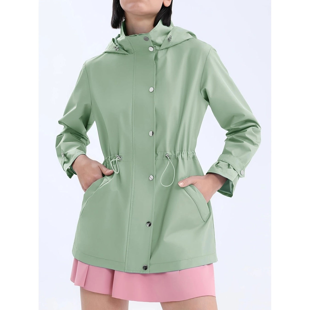 Saliegroene regenjas met capuchon, trekkoord in de taille en zakken met drukknoopklep | Boutique Moda